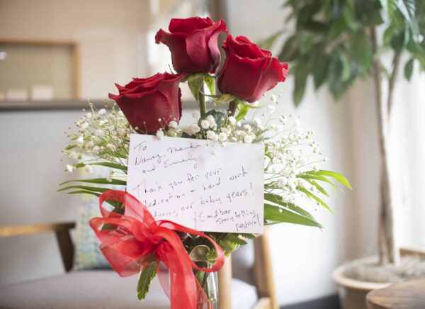 A vase of flowers with a thank you card