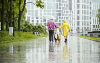 couple walking dog on a rainy sidewalk